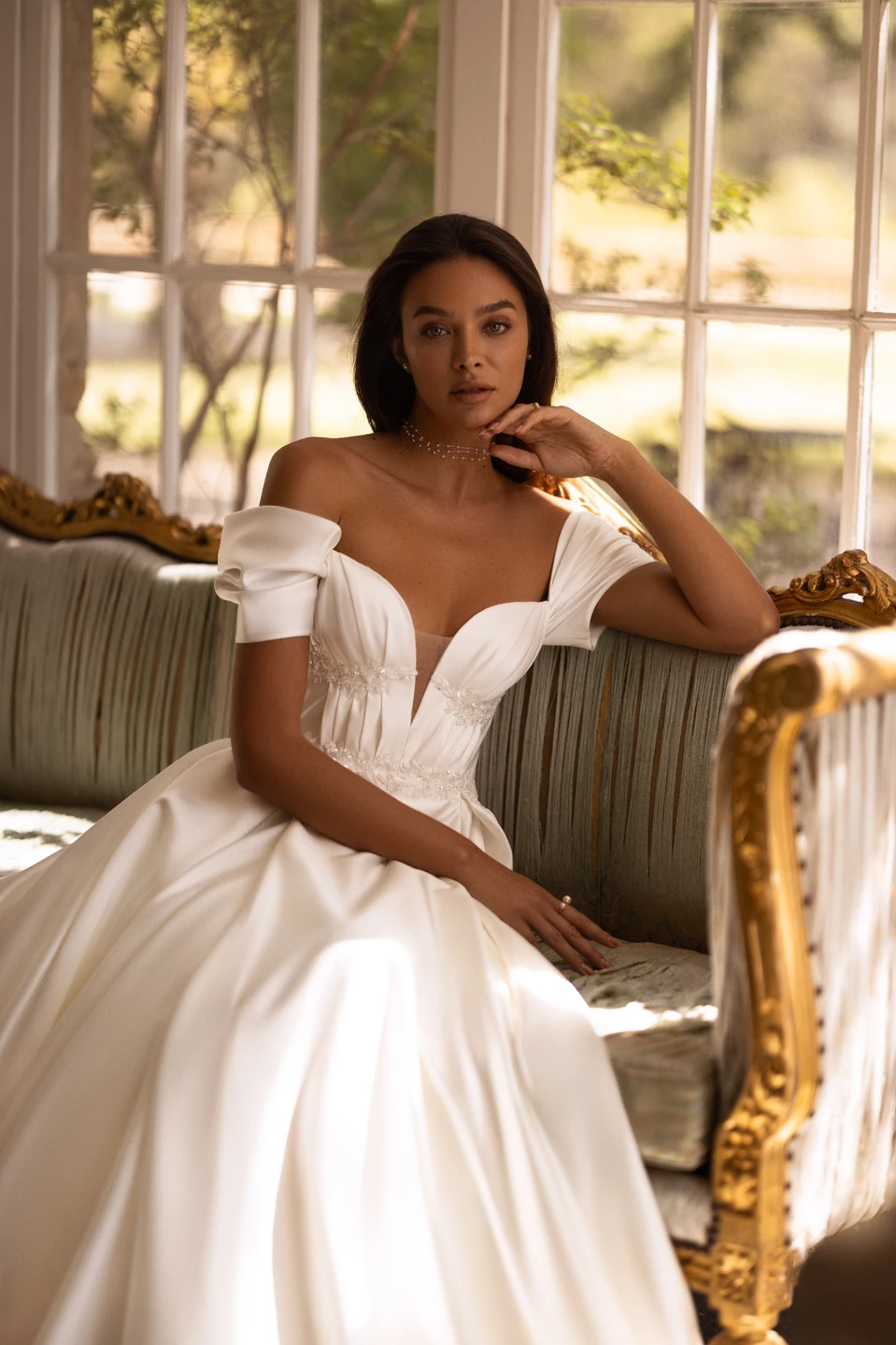 a girl sitting on a sofa and wearing a wedding dress